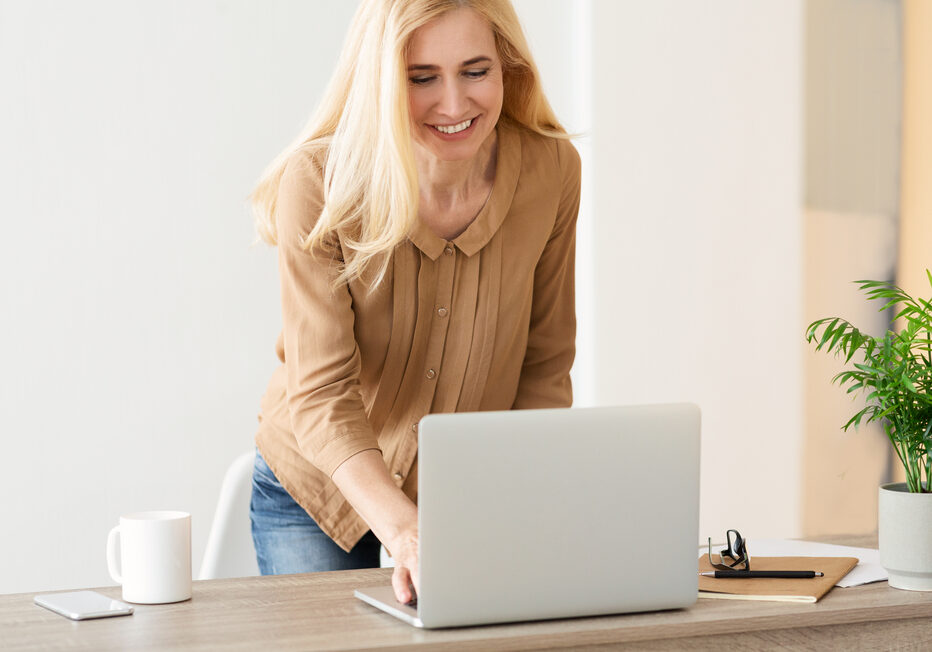 Responding On Business E-Mail. Woman Using Laptop, Standing In Office